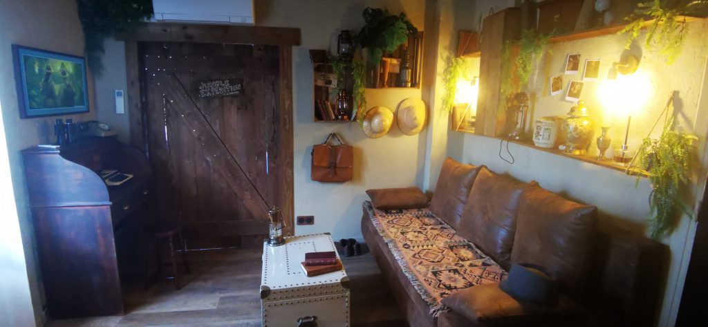 Le coin salon de la Suite des Aventuriers à Nice avec canapé convertible et déco d'explorateur